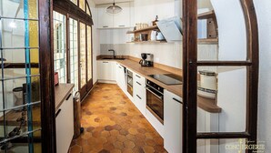 A kitchen with a hexagonal tile floor, wooden cabinets, and a built-in oven. - Château d'Aiguèze (Aiguèze)