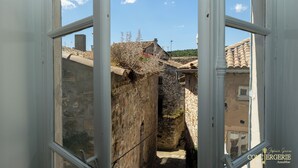 A narrow stone alleyway with traditional stone buildings, a clear sky, and a visible window frame. - Château d'Aiguèze (Aiguèze)