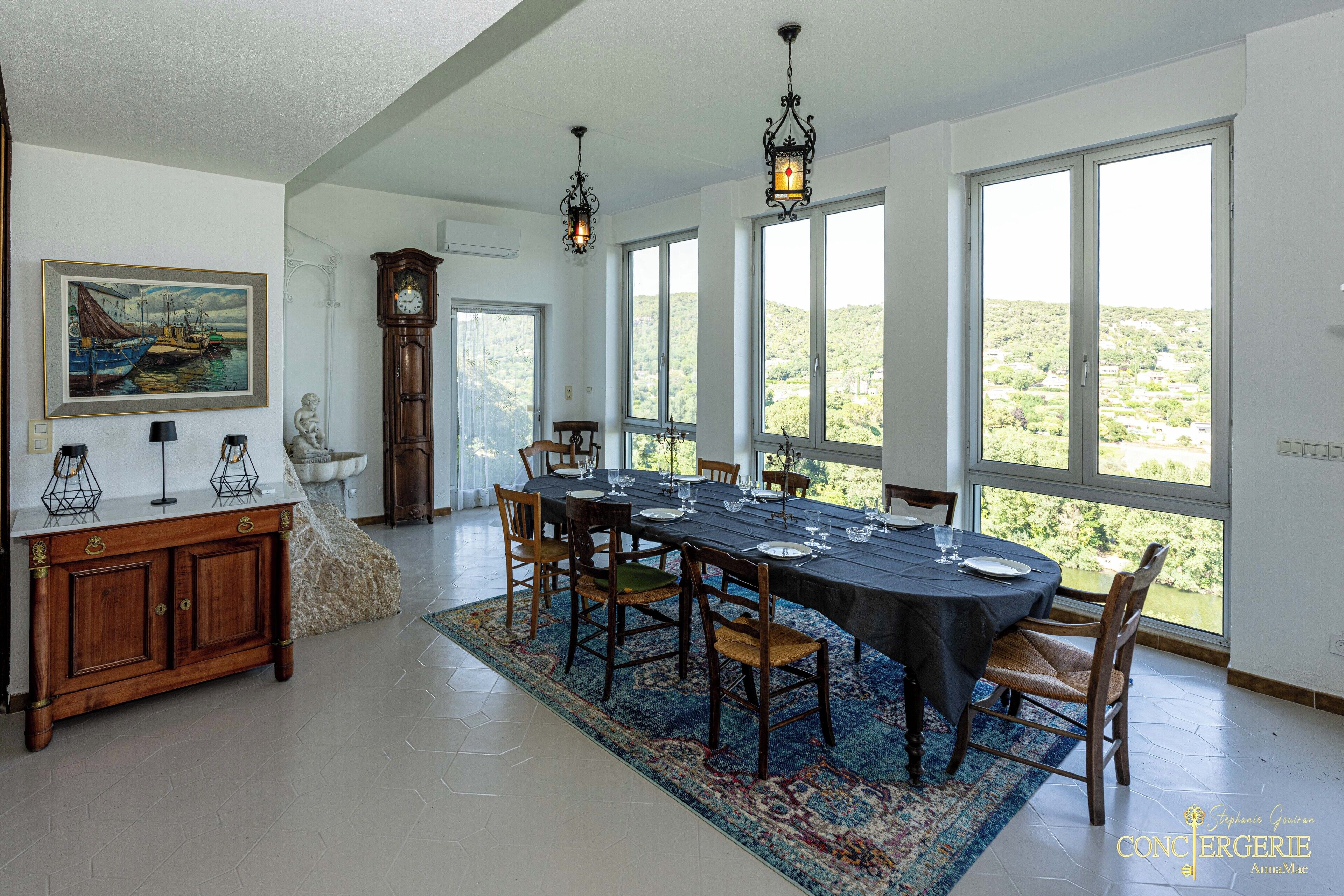 A dining room with a large table set for six, surrounded by chairs, a wooden cabinet, and a painting on the wall.