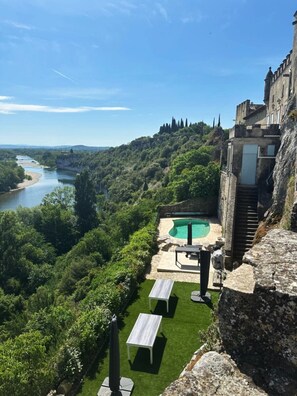 A pool area with a view of a river and forested hills. - Château d'Aiguèze (Aiguèze)