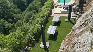 A lush garden with a swimming pool, outdoor seating, and a view of a river.
