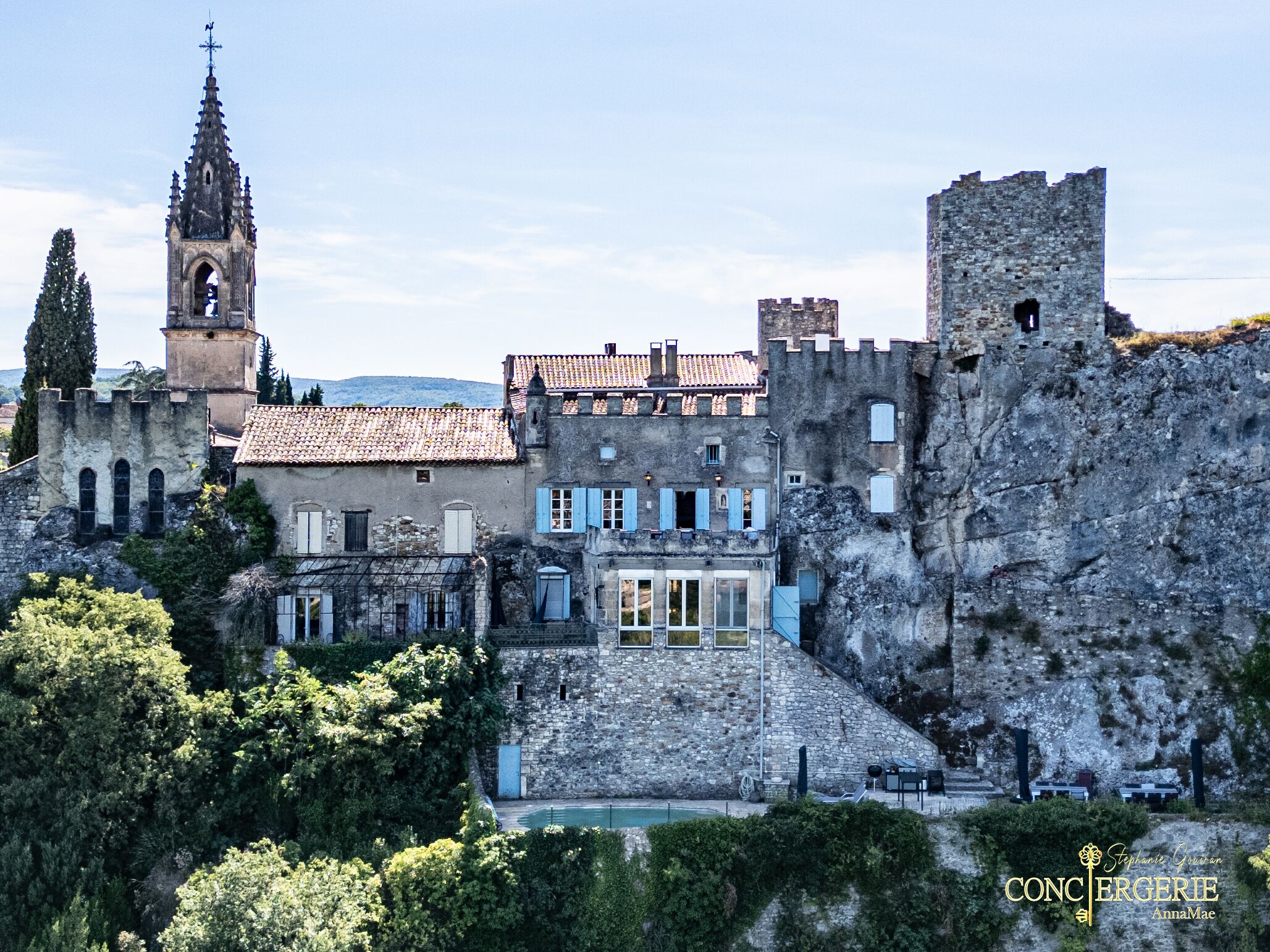 A historic building with a tower, stone walls, and a courtyard with outdoor seating.