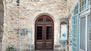 A stone building with a wooden door, a metal gate, and a blue window frame. - Château d'Aiguèze (Aiguèze)