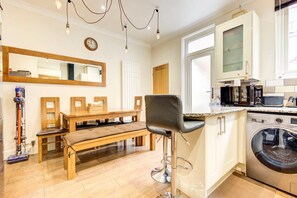 Une cuisine moderne avec une table à manger en bois, un tabouret de bar, un lave-linge et un four à micro-ondes.