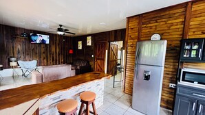 A kitchen with a wooden bar area, a refrigerator, and a television. - Cabaña el Descanso Fortuna (La Fortuna)