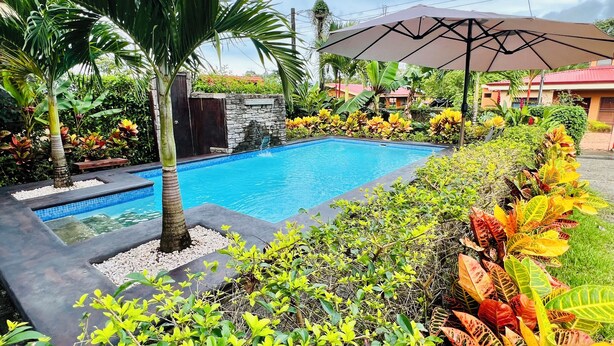 A swimming pool surrounded by lush greenery and a stone wall. - Cabaña el Descanso Fortuna (La Fortuna)