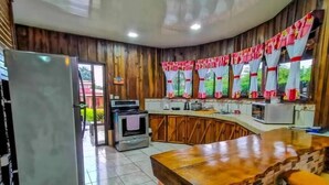 A kitchen with a refrigerator, stove, microwave, and bar stools. - Cabaña el Descanso Fortuna (La Fortuna)