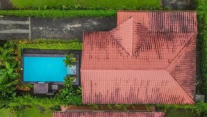 An aerial view of a property with a swimming pool, lush greenery, and a red-roofed building. - Cabaña el Descanso Fortuna (La Fortuna)