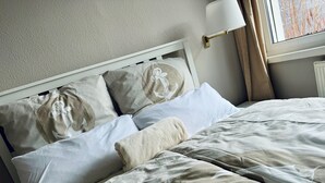 A neatly made bed with a patterned bedspread and pillows with anchor designs.