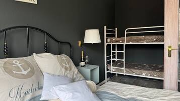 Une chambre avec un lit superposé, une table de chevet avec une lampe et un panneau accroché au mur.