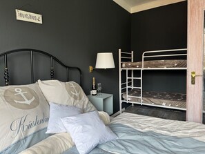 A bedroom with a bunk bed, a bedside table with a lamp, and a sign on the wall. - Pension Ostsee-Strand (Boergerende-Rethwisch)
