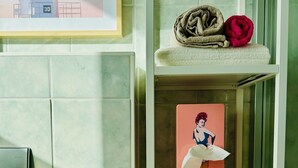 A bathroom with a toilet paper holder, a towel, and a framed picture on the wall.