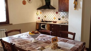 Uma mesa de jantar com um jogo de mesa, uma tigela de frutas e um letreiro com o menu.