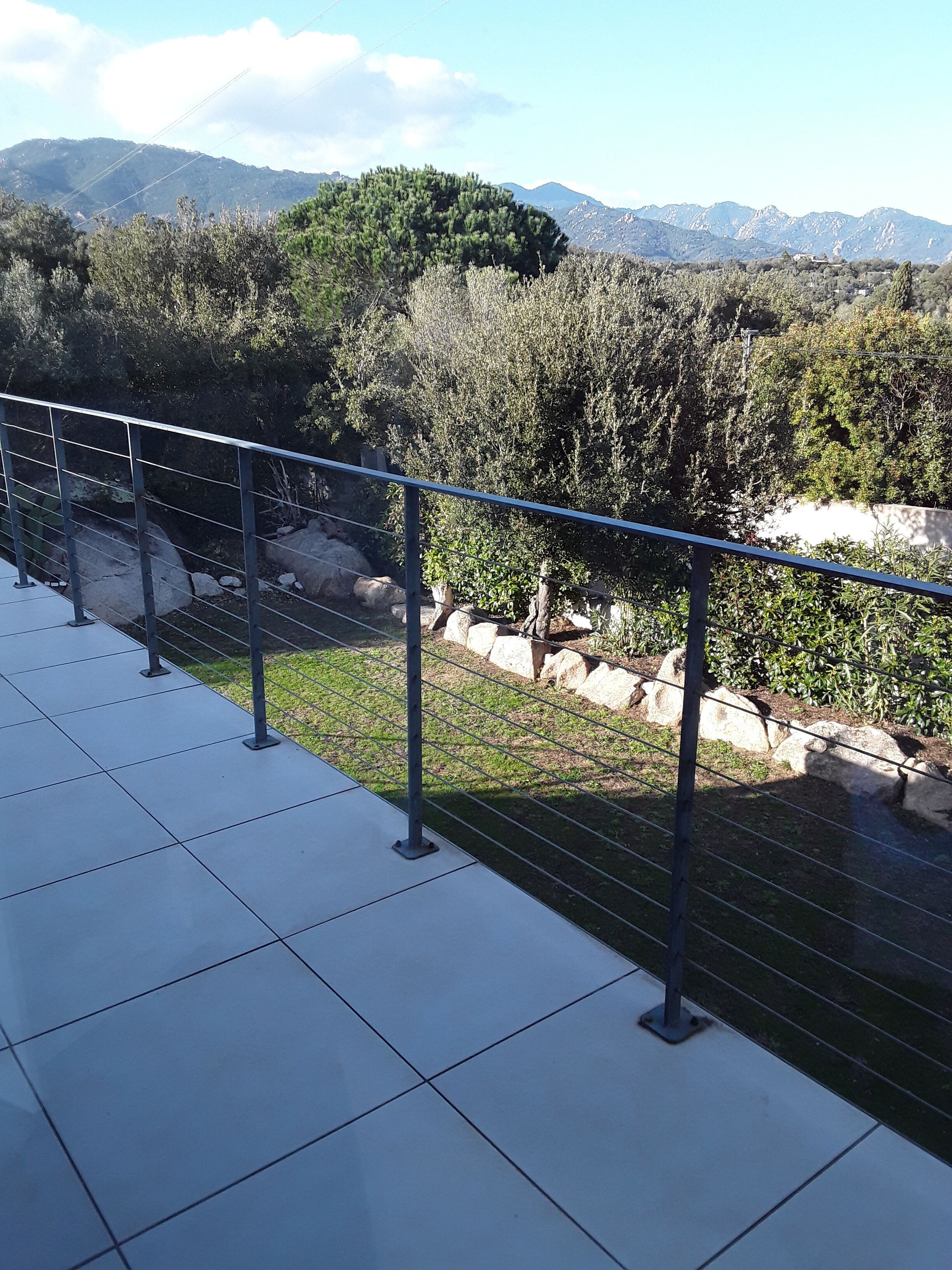 A balcony with a metal railing overlooking a mountainous landscape.