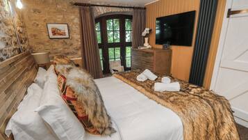 A bed with a fur throw, a wooden headboard, and a TV mounted on the wall.
