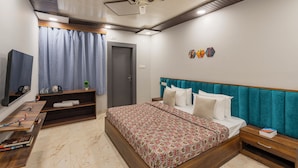 Un dormitorio con cama, televisor, estantería con libros y una puerta.