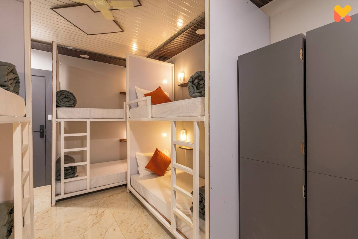 Une chambre avec un lit superposé, une armoire et un ventilateur de plafond.