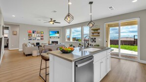 A spacious kitchen with a central island, a dining area with a sofa, and a large window offering a view of the outdoors. - 5BD Modern Home: Pool/Ping-Pong/Arcade - Wine City (Fairfield)