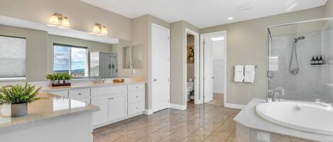 A spacious bathroom with a large bathtub, a shower area, and a vanity with a sink.