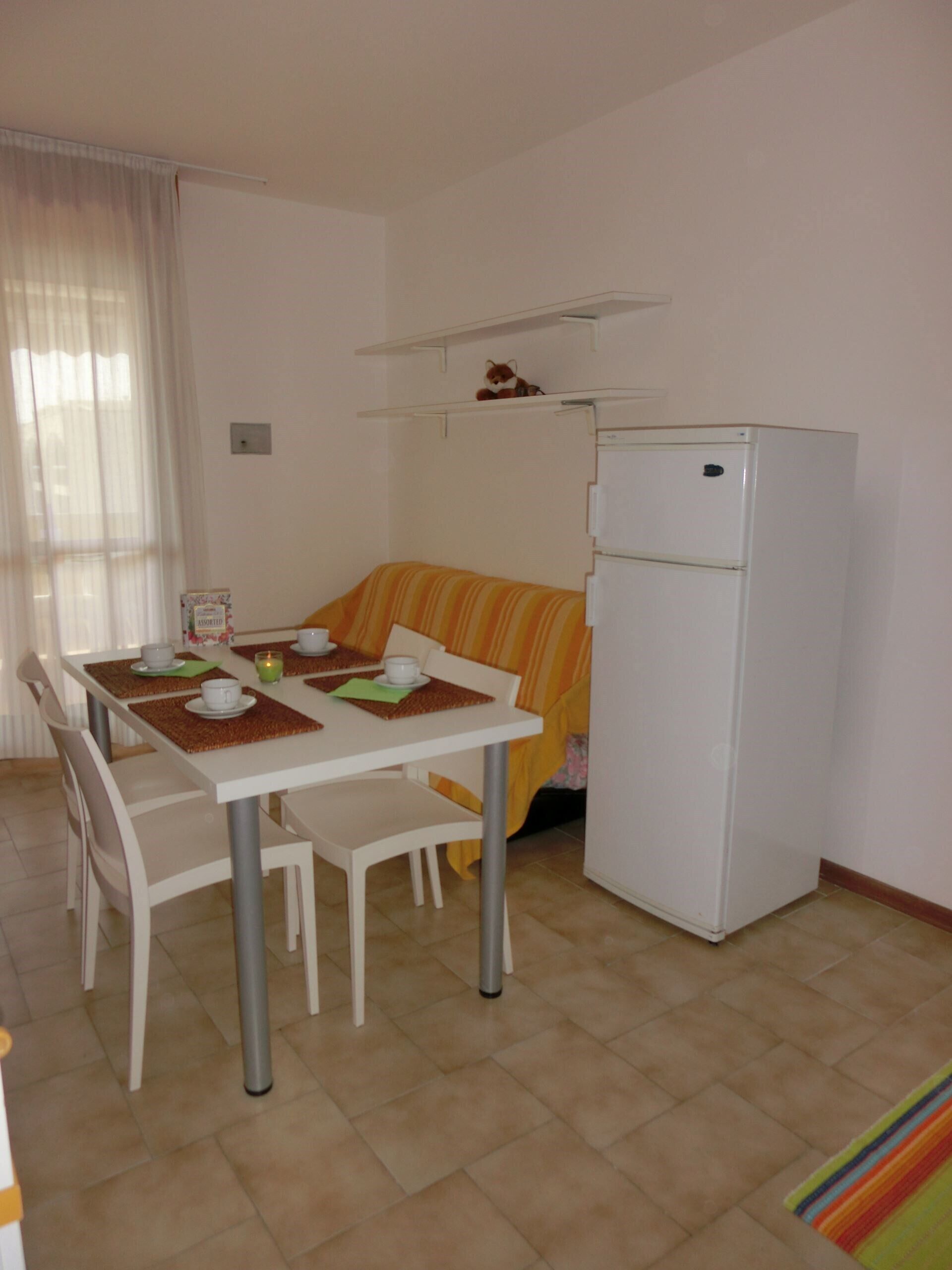 Une cuisine compacte comprenant une table à manger pour quatre personnes, un réfrigérateur et un canapé.