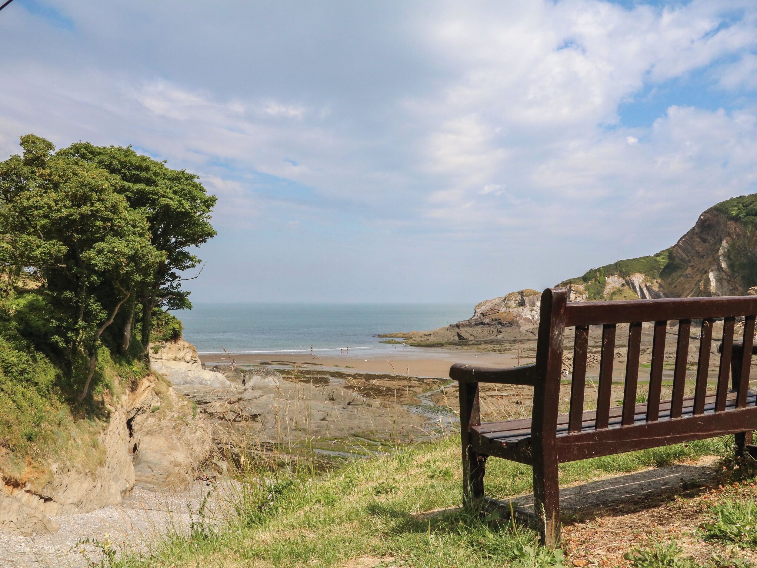 A bench overlooking a coastal landscape with cliffs and a beach.