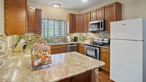 A kitchen with wooden cabinets, granite countertops, a refrigerator, a microwave, and a dishwasher. - ~Bamboo Oasis Relaxing Hot Tub Family Time~ Get to Anywhere in SA in 20 mins! (San Antonio)