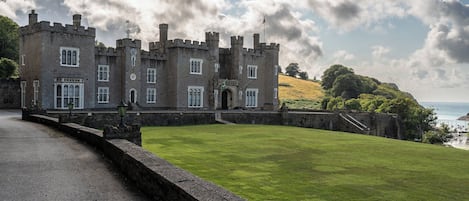 A castle-like building with a paved pathway leading to a grassy area.