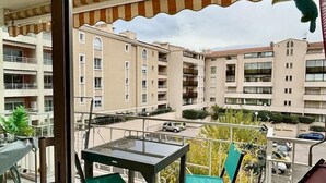A balcony with a table and chairs, overlooking a residential area with multiple buildings. - Beautiful 65 m² flat (Saint-Raphaël)