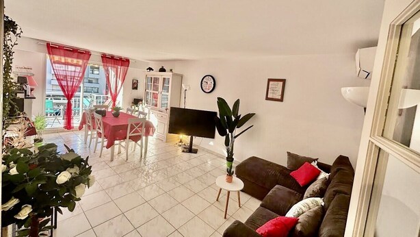 A living room with a sofa, a TV, and a dining area with a table and chairs. - Beautiful 65 m² flat (Saint-Raphaël)