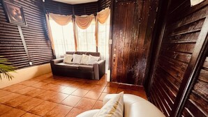 Ein Zimmer mit einer Couch, einem Sessel und einer Holztür.