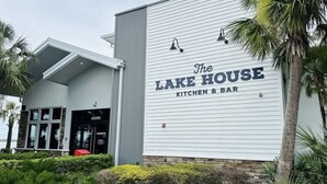 The Lake House, eine Küche und Bar mit modernem Design, inklusive einer großen Schautafel und einem gepflegten Außenbereich mit Bepflanzung.