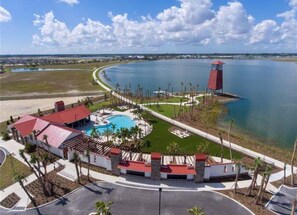 Un resort con piscina, una torre roja y vistas al agua y paisaje circundante.