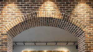 A reception area with a brick archway, a marble reception desk, a large wall with a geometric pattern, and a tiled floor. - Bomonti Suites (Istanbul)