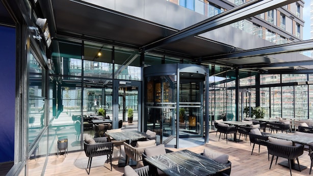 A modern outdoor seating area with glass walls, tables, and chairs. - Bomonti Suites (Istanbul)