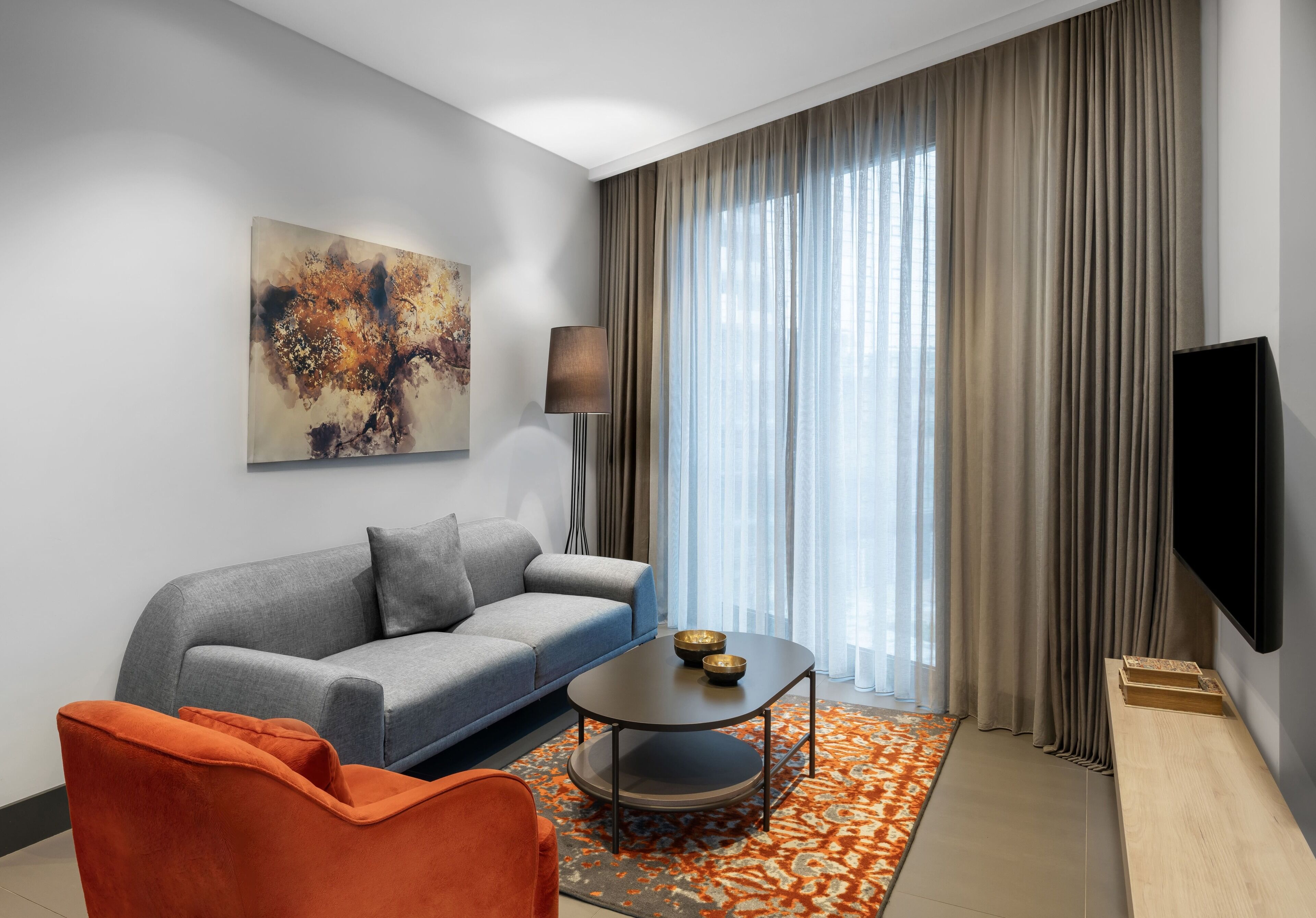 Ein modernes Wohnzimmer mit einer Couch, einem Couchtisch und einem orangefarbenen Sessel.