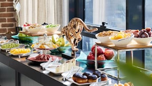 A buffet with various food items, a decorative bird sculpture, and a window with a view of buildings. - Bomonti Suites (Istanbul)