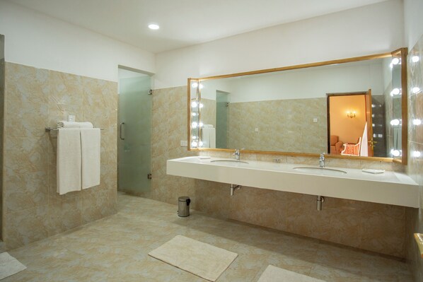 Une salle de bain moderne avec deux vasques, un grand miroir avec éclairage intégré et un porte-serviettes.