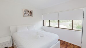 Une chambre à coucher avec un lit, une fenêtre et un tableau au mur.
