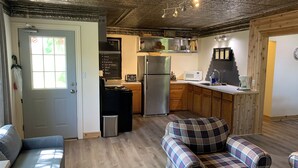 Une cuisine chaleureuse avec un plafond en bois, un réfrigérateur, un four à micro-ondes et un tableau noir servant de menu.