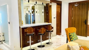 A modern living room with a sofa, a wooden door, and a bar area with stools.