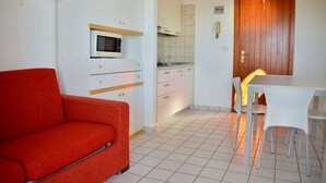 A compact living space with a kitchenette, a dining area, and a red sofa.