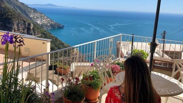 A balcony with a view of the sea, potted plants, and outdoor furniture. - Casa Toby Positano  (Campania)