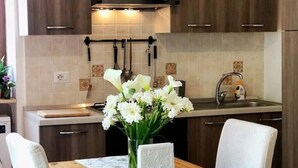 A kitchen with wooden cabinets, a sink, and a vase of white flowers on the counter. - Casa Toby Positano  (Campania)