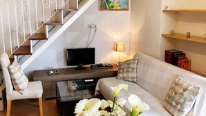 A living room with a sofa, a coffee table, a TV, and a staircase. - Casa Toby Positano  (Campania)