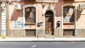 Um edifício com fachada marrom, duas janelas em arco e uma porta central.