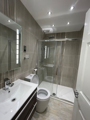 Un bagno moderno con cabina doccia in vetro, un lavandino bianco e un water.