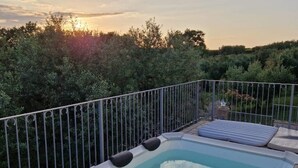 A hot tub with a metal railing, surrounded by lush greenery.