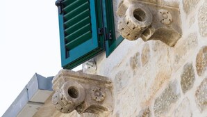 Edifici de pedra amb persianes verdes i elements decoratius de pedra.
