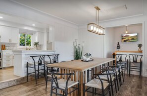 A modern kitchen with white cabinetry, a wooden dining table, and black chairs. - Pickleball Disney Resort w/ heated pool &sleeps 12 (Santa Ana)