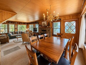 Un interior de madera con una gran mesa de comedor, sillas, un sofá y una chimenea.